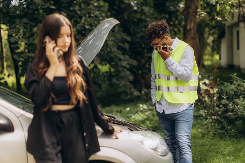 Woman and man looking at inside of a car on the phone. 