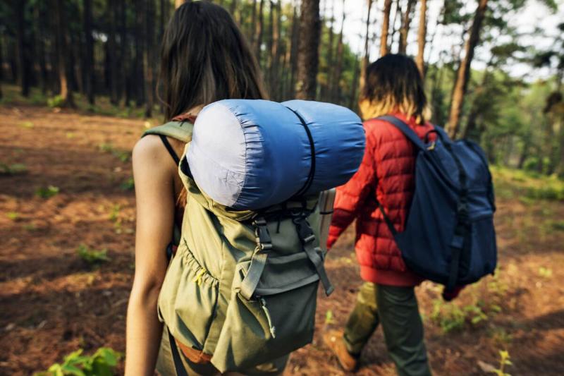 A woman with a sleeping bag on her backpack. 