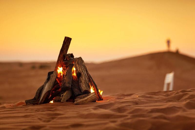 A campfire in a desert at sunset. 