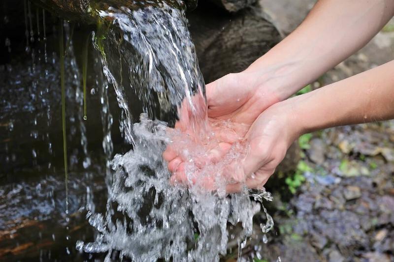 Hands catching water from a mountain stream. 