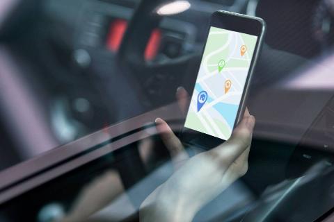 Hands holding a phone showing a map in car. 