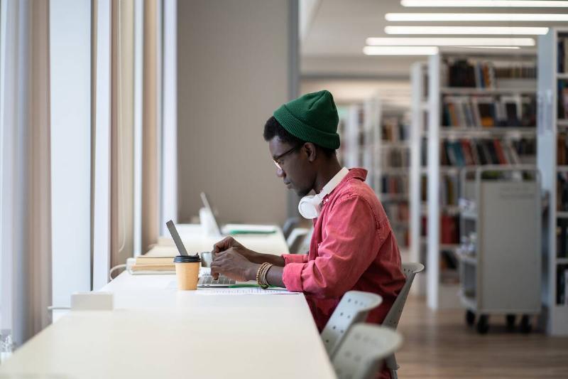 Man doing research at a desk in a library. 