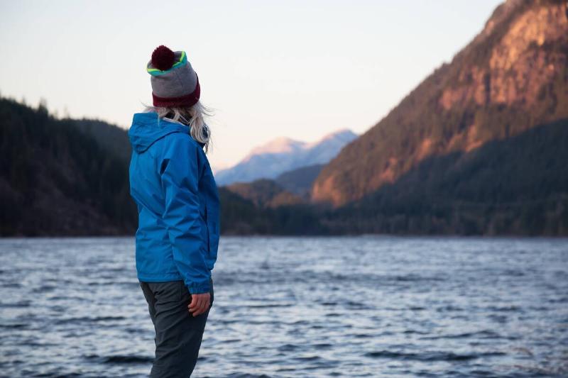 Woman in waterproof jacket watching lake. 