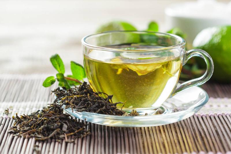 A clear glass mug of green tea. 