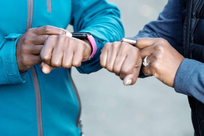 Hands of unrecognizable black women checking their smart watches.