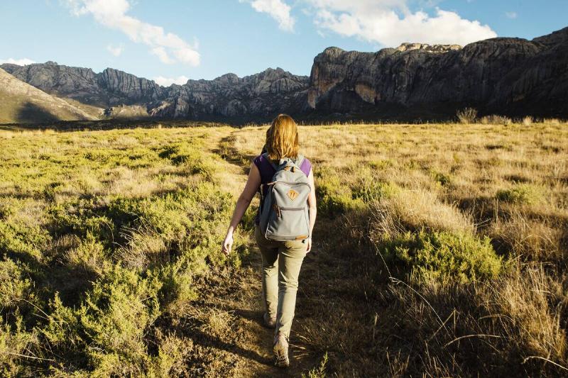 Hiker exploring a scenic mountain trail during golden hour.
