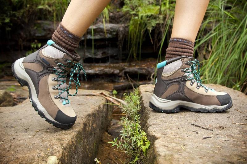 Fit young hiker crosses stone steps in hiking boots.