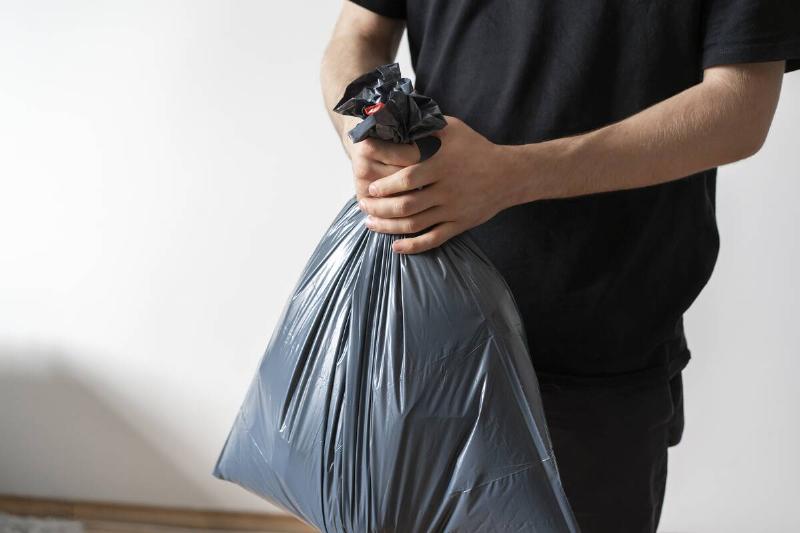 Hands tightly holding a garbage bag. 
