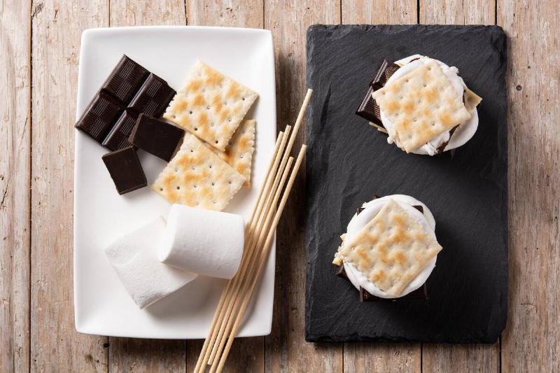 Homemade s'mores and ingredients on wooden table.