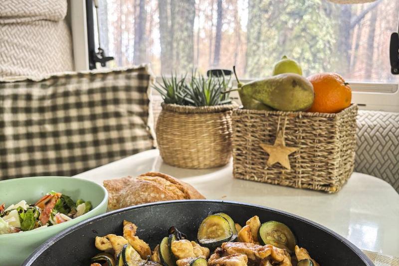 Interior of camper van motorhome with food on the table in front of a window. 