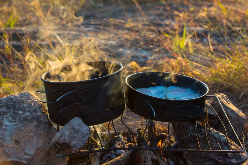Cooking pans over an open camping fire. 
