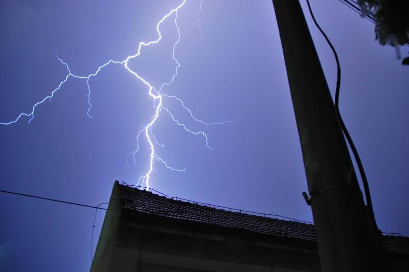 A lightening strike near a house at night. 