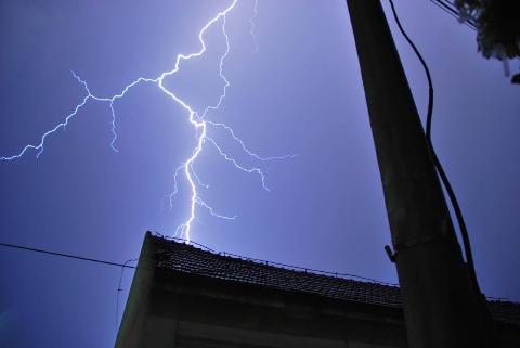 A lightening strike near a house at night. 
