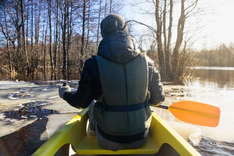 Man on canoe with paddle and life jacket.