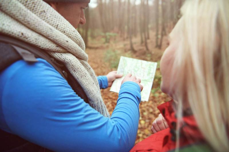 Man pointing on the paper map with another woman. 