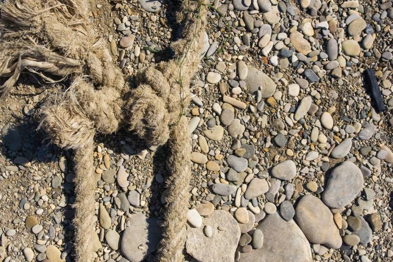 Knots tied in old rope on a sandy, pebble landscape. 