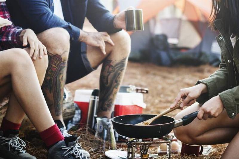 Friends eating and cooking around a campfire. 