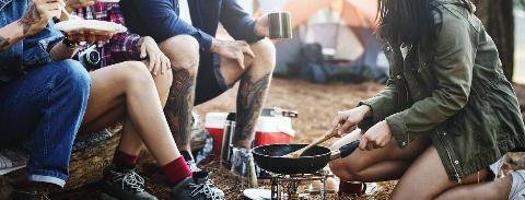 Friends eating and cooking around a campfire. 