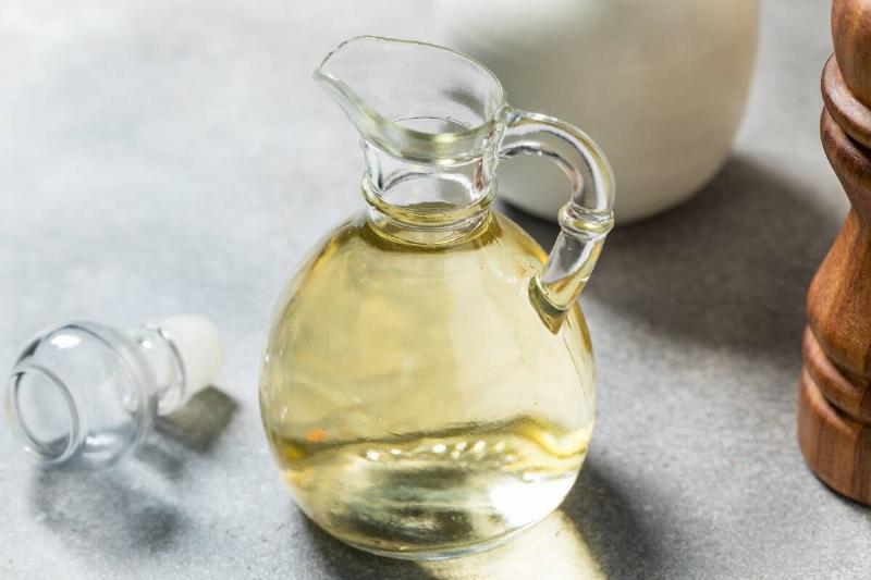 A glass jug with white vinegar inside of it. 
