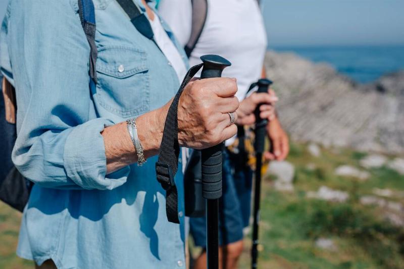 Senior man and woman practicing trekking outdoors with hiking poles. 