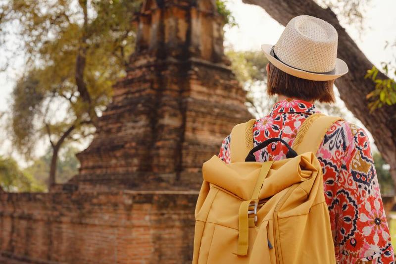 Young female tourist in dress exploring historic park of Ayutthaya, Thailand.