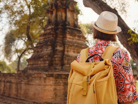 Young female tourist in dress exploring historic park of Ayutthaya, Thailand.