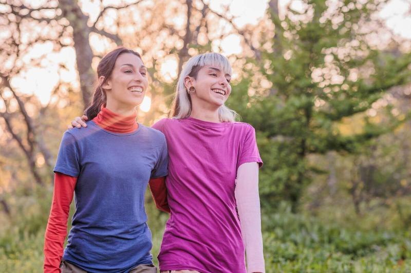 Two friends wearing long-sleeve shirts in nature. 
