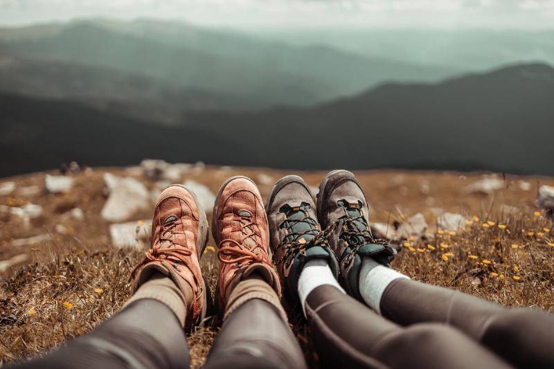Two people sitting in nature, wearing hiking boots. 
