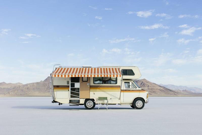 Vintage Dodge Sportsman RV with striped canopy parked on Salt Flats.