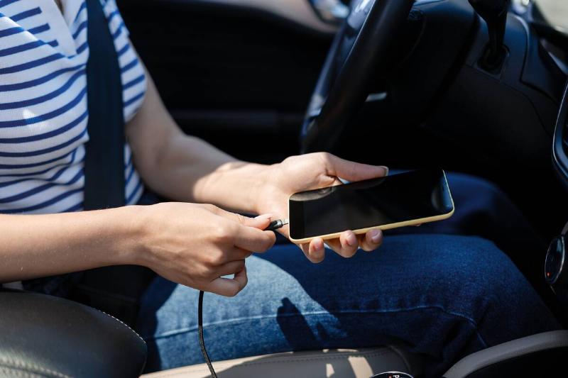 Woman charging her smartphone in a car.