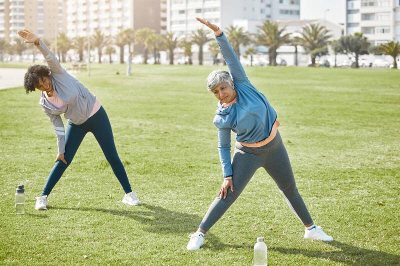 Two women stretching in a park. 