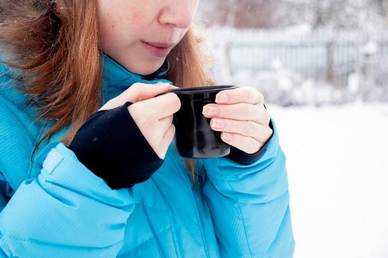 Woman holding a hot drink in a mug. 