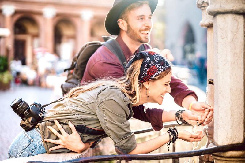 A young couple having fun at a fountain while traveling. 