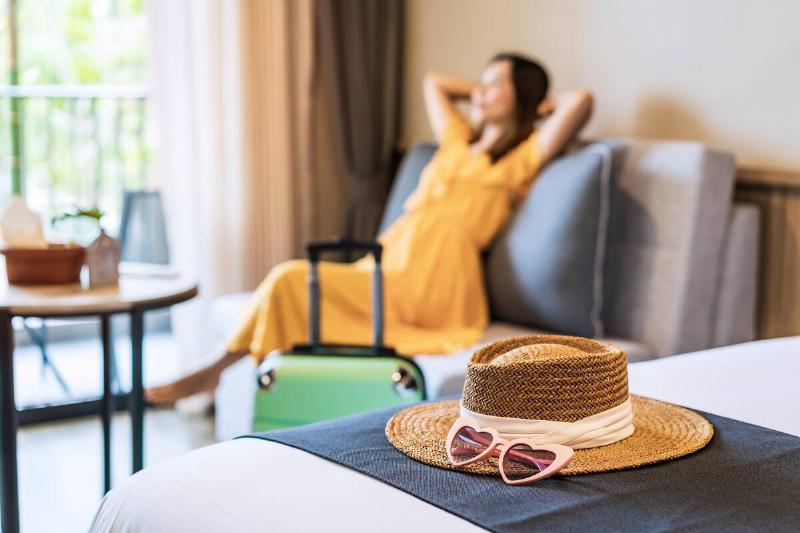 Young woman traveler sitting and relaxing in a hotel room while on summer vacation.