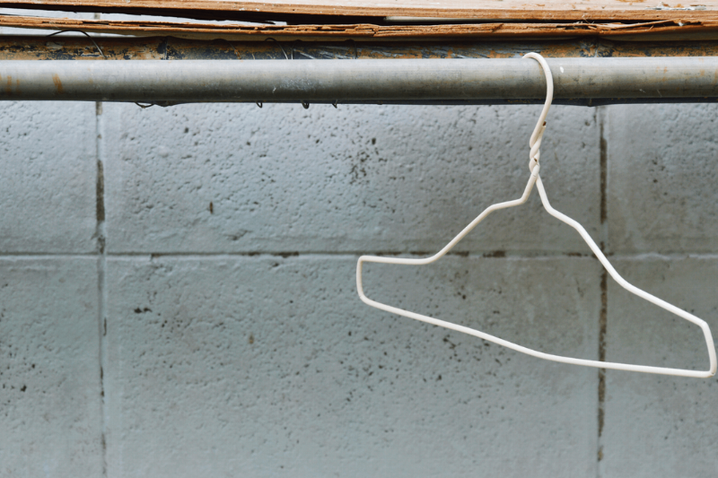 A wire clothes hanger hanging from a pipe. 