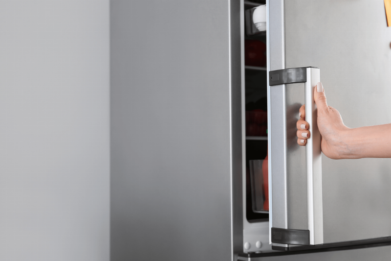 A hand holding a fridge door.