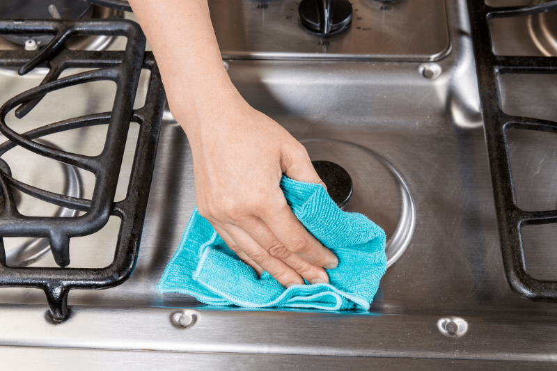 Wiping a metal oven with a cloth. 