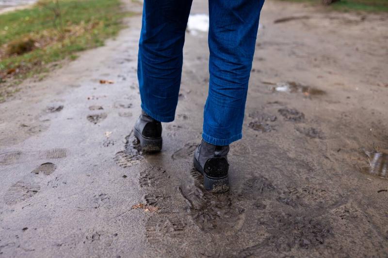 A person's boots, walking in mud. 