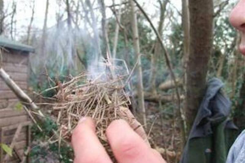 Blowing on tinder to increase smoke. 