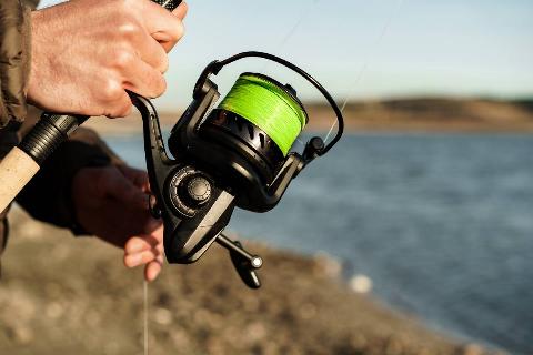 Fisherman hands holding fishing rod close up photo.