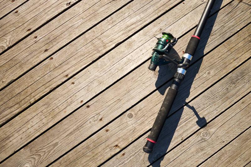 Fishing rod lying diagonally on wooden dock.