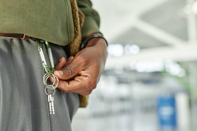 A man showing keys on a key ring attached to his belt. 