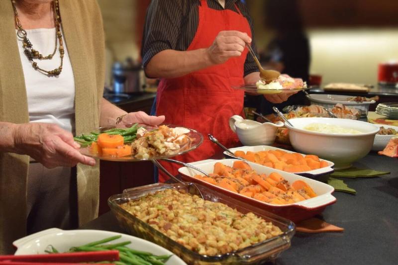 People serving themselves food at a potluck. 