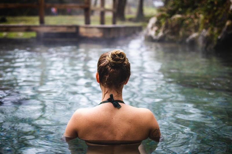 The back of a woman's head soaking in hot springs. 