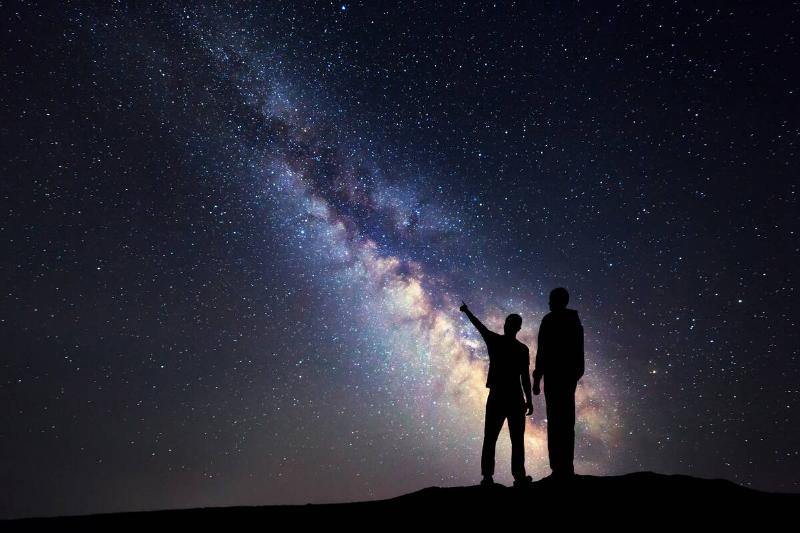 The shadow of two people standing together, looking at stars.