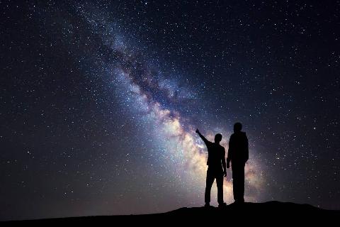 The shadow of two people standing together, looking at stars.