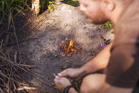 A man lighting a campfire. 