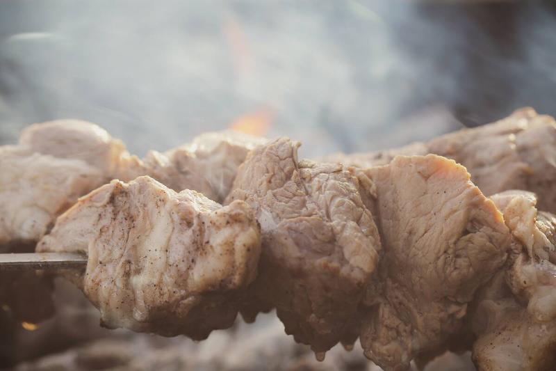 Meat on a stick, cooking outside. 