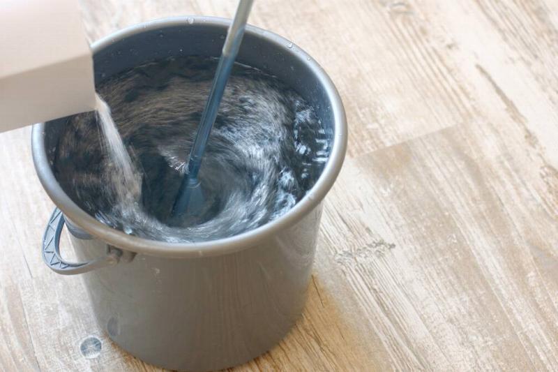 Pouring cleaner into a bucket of water.