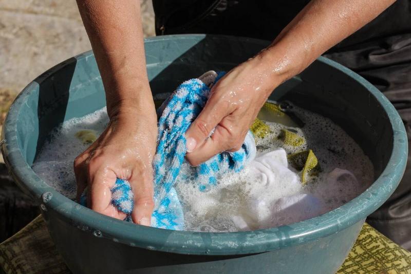 Clothes being washed by hand in a bucket. 
